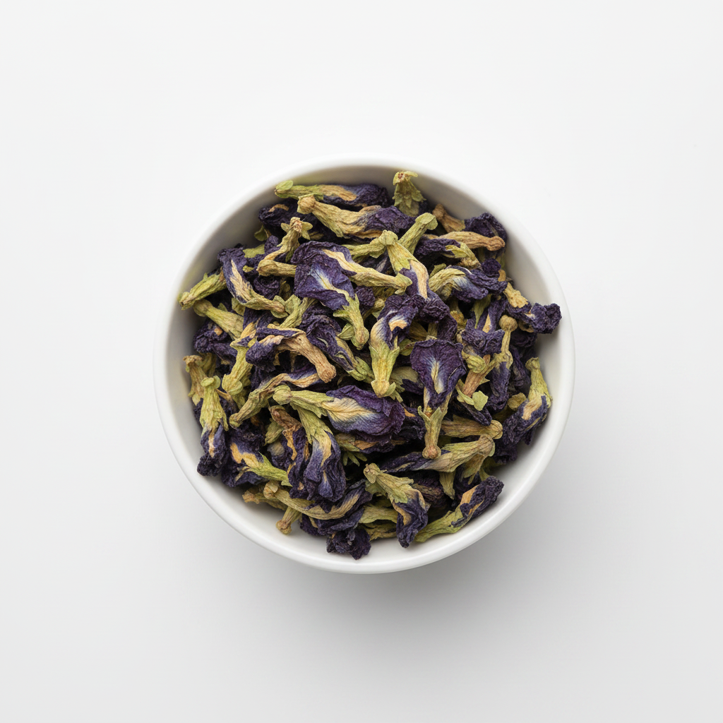 Whole dried butterfly pea flowers in a white ceramic bowl on a white background