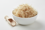 Dried slippery elm inner bark cut and sifted stringy fibrous pale tan strands in a white ceramic bowl with wooden scoop