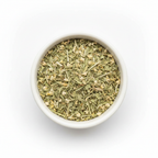Cut and sifted eyebright herb in a white ceramic bowl on a white background, small mixed green leaf and stem pieces with tiny dried flower fragments