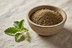 Organic dried tulsi holy basil herb finely cut in a ceramic bowl with fresh tulsi sprigs