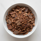 Ceylon cinnamon chips in a white ceramic bowl, chunky dark reddish-brown bark pieces overhead flat lay