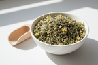 Dried yarrow cut and sifted herb in a white ceramic bowl with wooden scoop