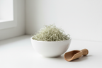 Dried usnea lichen stringy grayish-green strands in a white ceramic bowl with wooden scoop